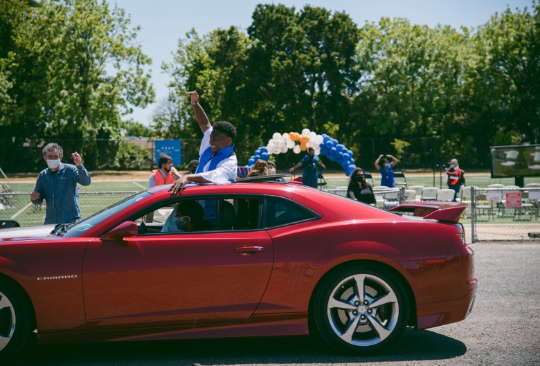 Sir cheers from the sunroof of a car while driving away to make room for the following commencement ceremony at Madison Park Academy on May 21, 2021. Photo by Marissa Leshnov for CalMatters